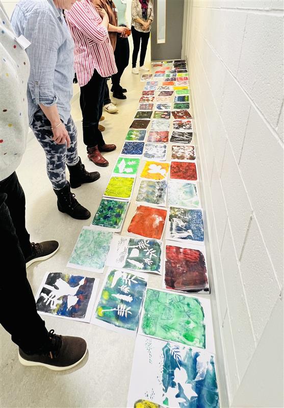 Photograph of participants looking at their artworks from an in person workshop